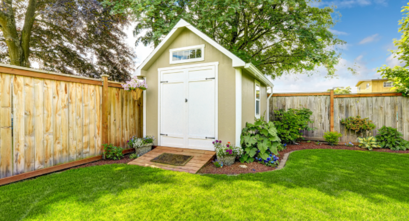 Shed in garden with flowers around the edge.